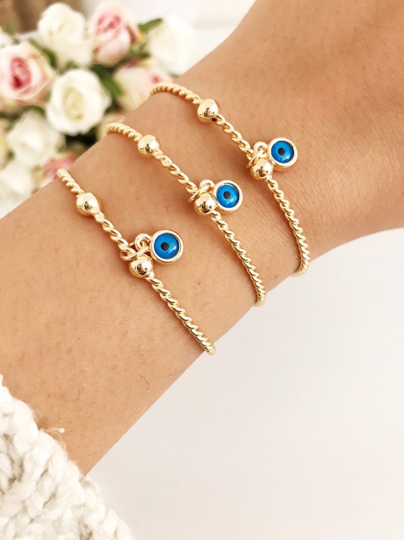 Gold Evil Eye Bangle Bracelet featuring a movable blue evil eye charm, crafted from tarnish-resistant stainless steel.