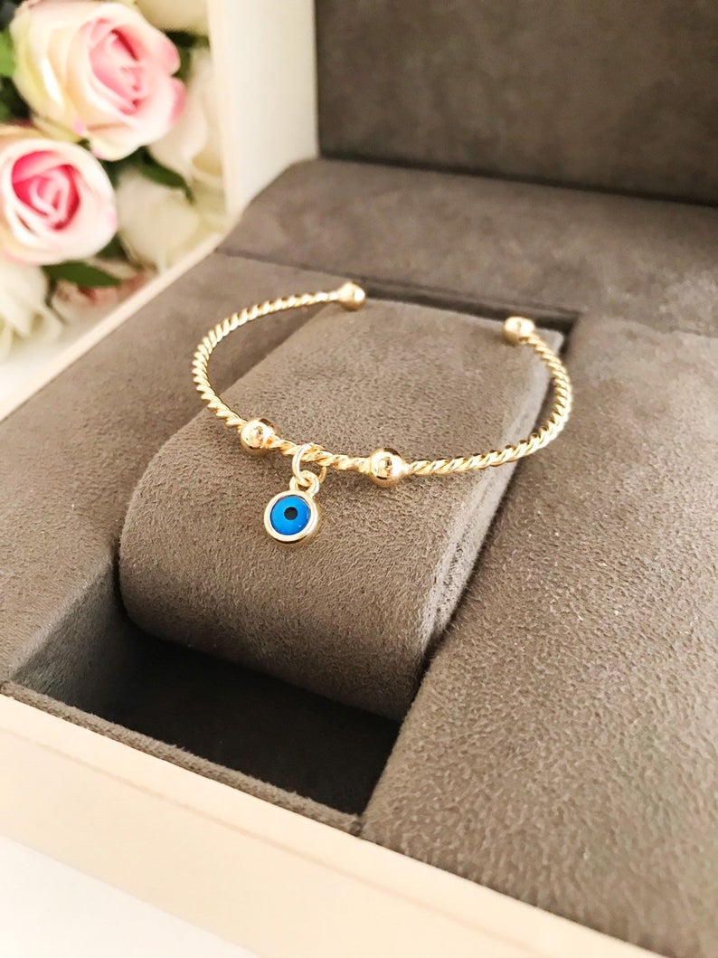 Gold Evil Eye Bangle Bracelet featuring a movable blue evil eye charm, crafted from tarnish-resistant stainless steel.