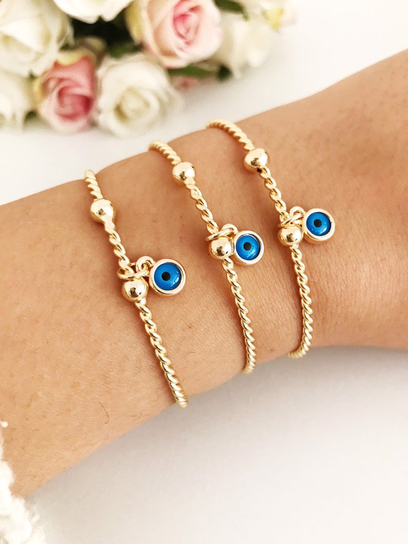 Gold Evil Eye Bangle Bracelet featuring a movable blue evil eye charm, crafted from tarnish-resistant stainless steel.