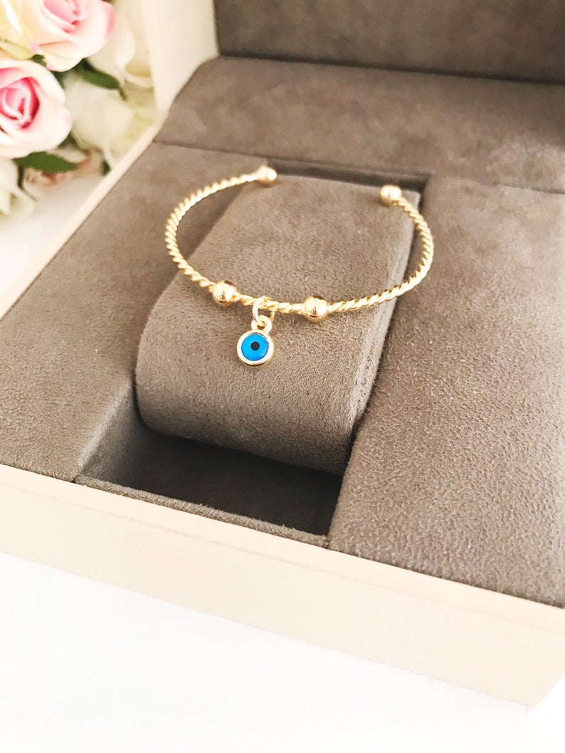 Gold Evil Eye Bangle Bracelet featuring a movable blue evil eye charm, crafted from tarnish-resistant stainless steel.