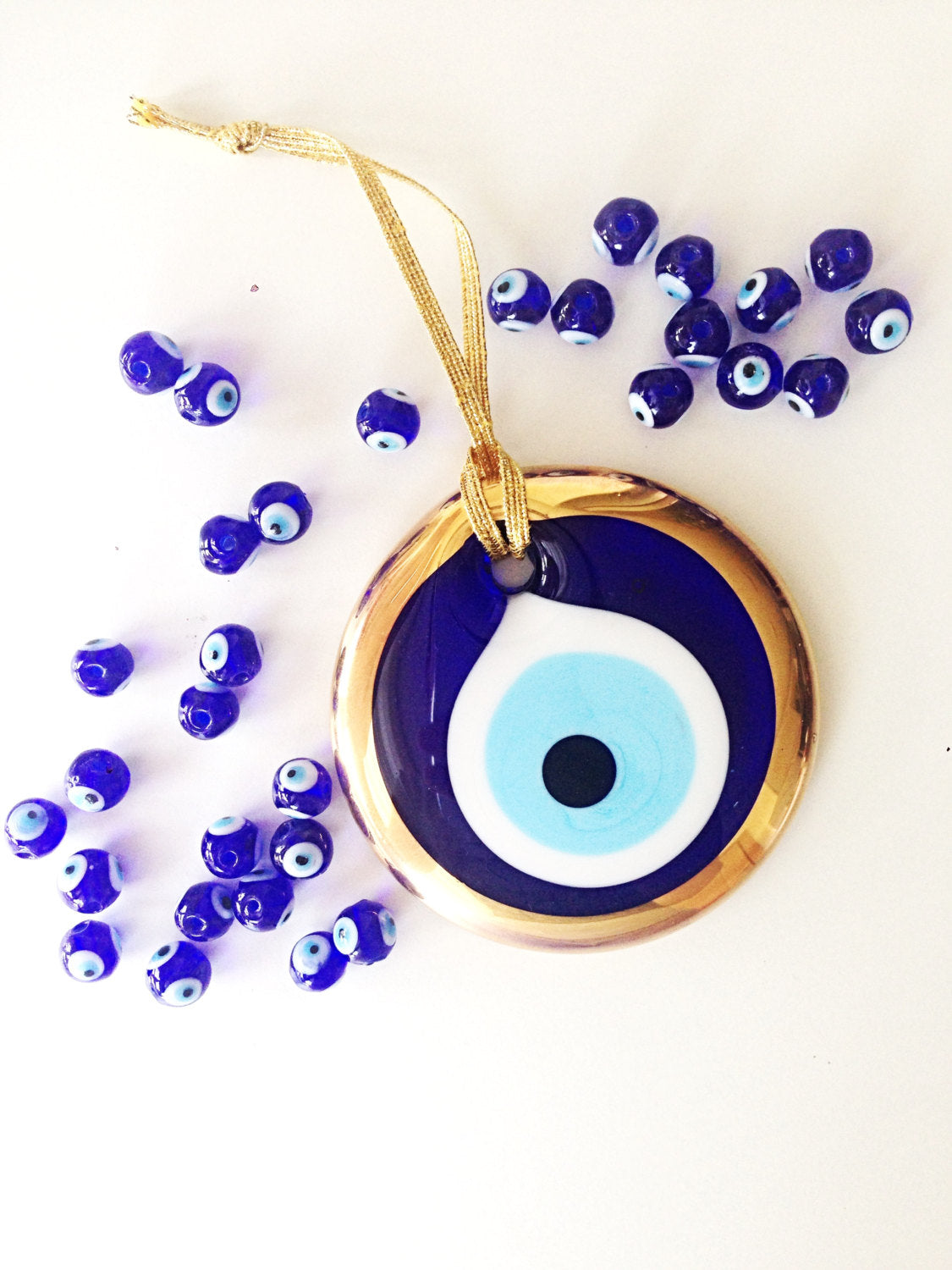 A 7cm handmade gold evil eye bead wall hanging with a gold rope, featuring intricate designs and vibrant colors.