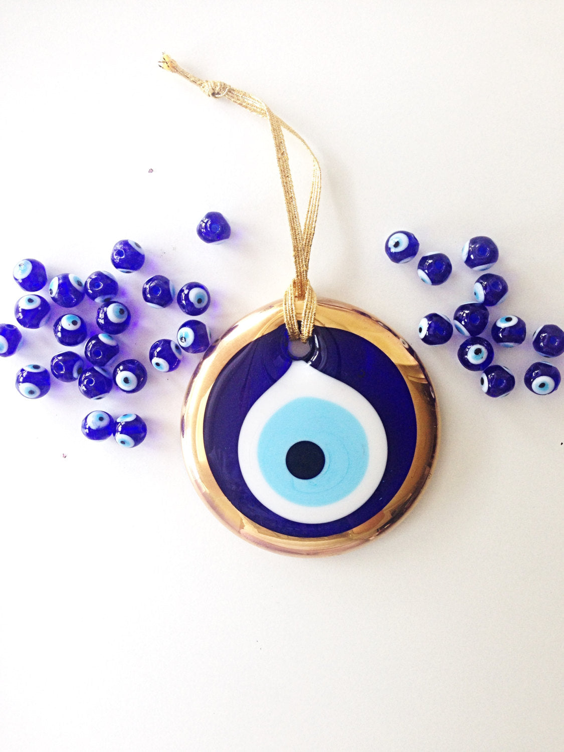 A 7cm handmade gold evil eye bead wall hanging with a gold rope, featuring intricate designs and vibrant colors.