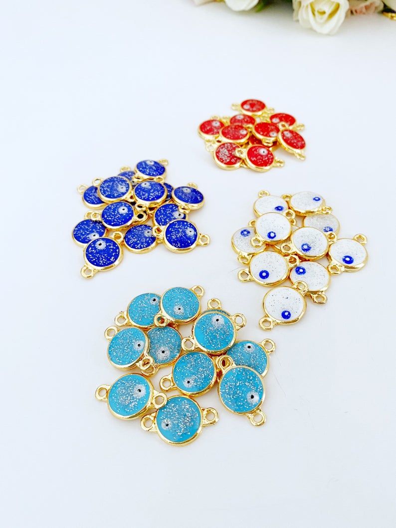 A collection of five gold evil eye beads with a glittering finish, showcasing their intricate design and vibrant colors, perfect for DIY jewelry projects.