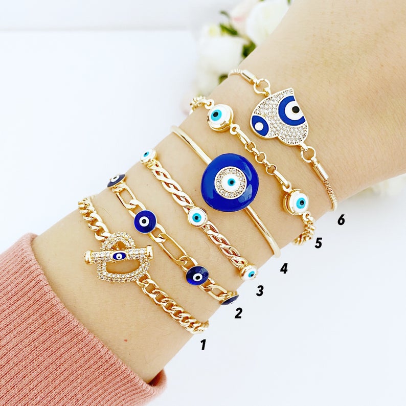 Gold Evil Eye Bracelet featuring a blue charm, adjustable stainless steel cuff design, perfect for everyday wear.