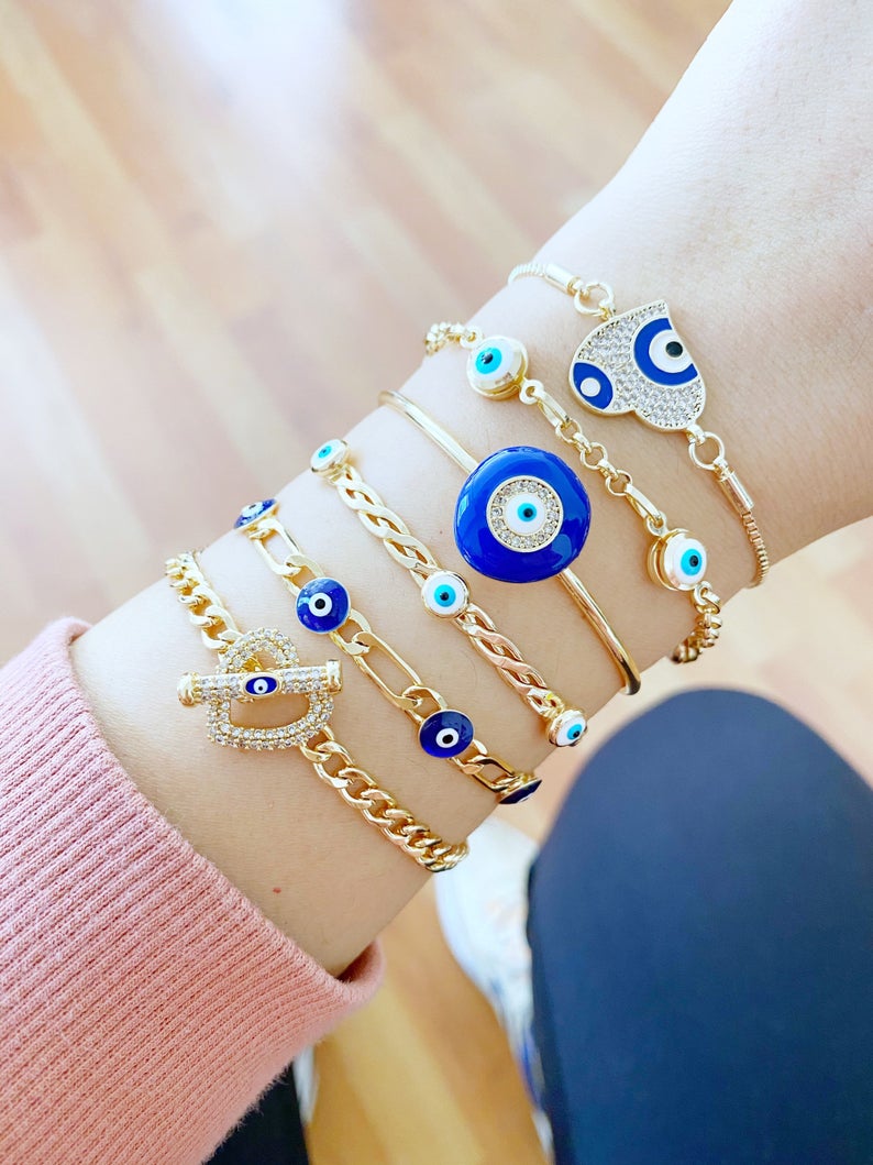 Gold Evil Eye Bracelet featuring a blue charm, adjustable stainless steel cuff design, perfect for everyday wear.