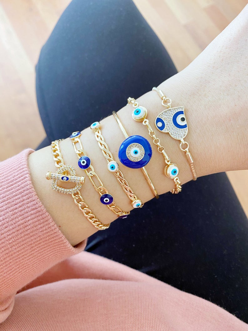 Gold Evil Eye Bracelet featuring a blue charm, adjustable stainless steel cuff design, perfect for everyday wear.