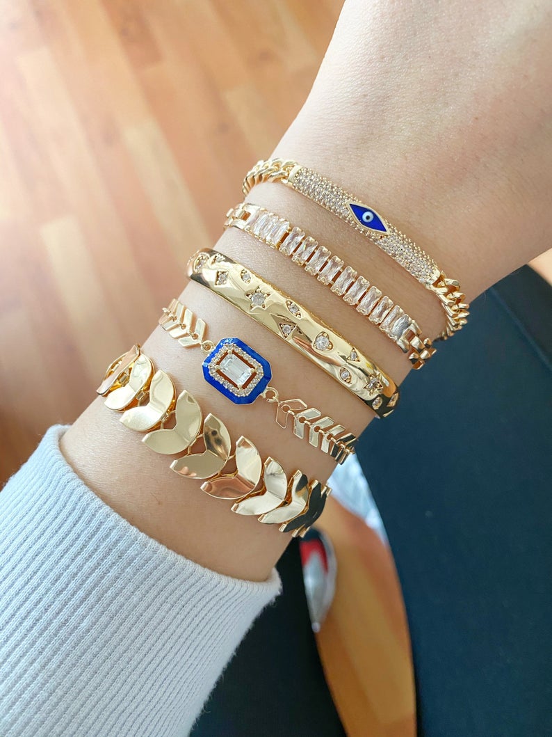 Gold Evil Eye Bracelet featuring a blue evil eye charm, crafted from durable stainless steel with a gold finish, adjustable design for all wrist sizes.