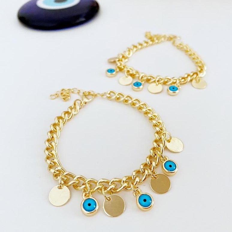 Gold Evil Eye Bracelet featuring a gold link chain, blue evil eye bead, and mini gold disc charm, showcasing its elegant design and craftsmanship.