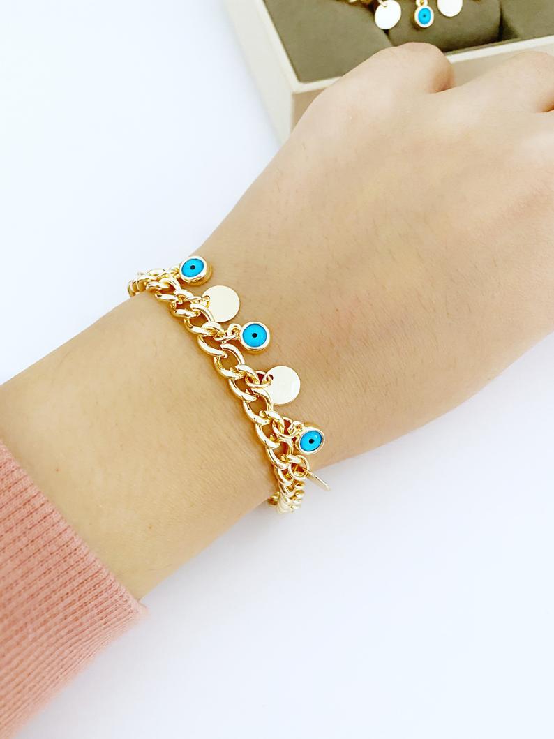 Gold Evil Eye Bracelet featuring a gold link chain, blue evil eye bead, and mini gold disc charm, showcasing its elegant design and craftsmanship.