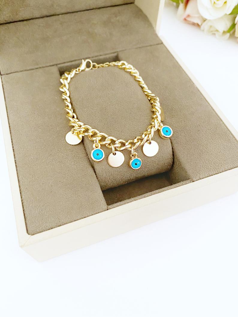 Gold Evil Eye Bracelet featuring a gold link chain, blue evil eye bead, and mini gold disc charm, showcasing its elegant design and craftsmanship.