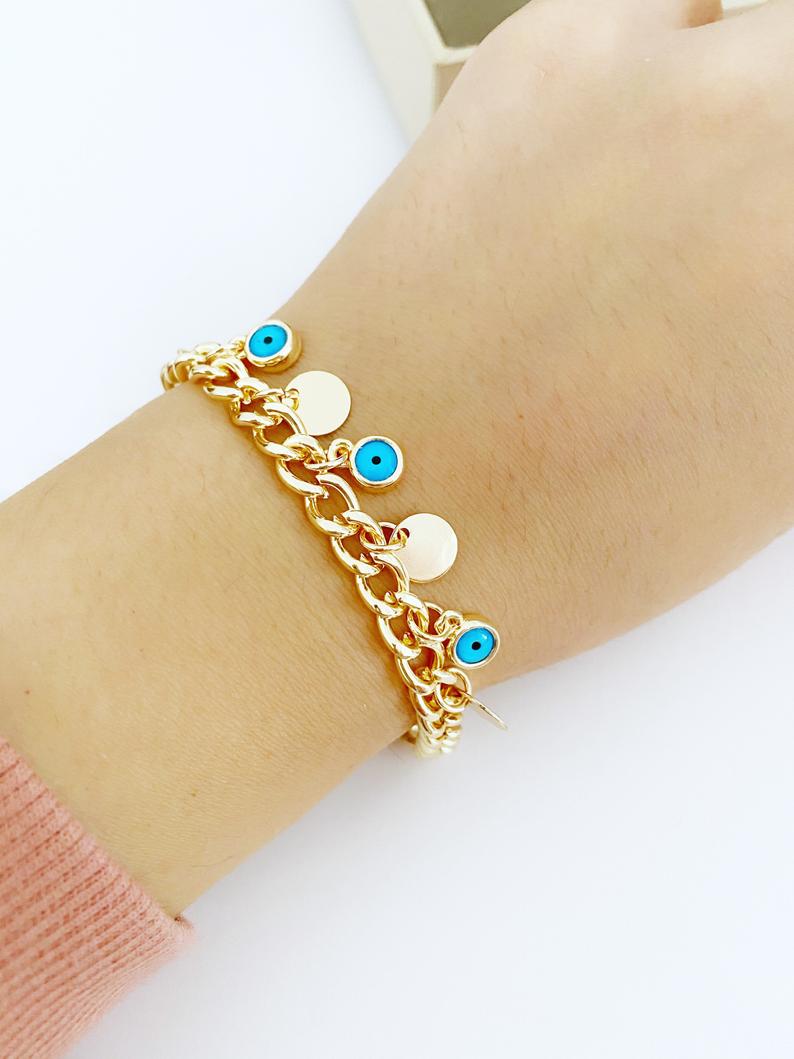 Gold Evil Eye Bracelet featuring a gold link chain, blue evil eye bead, and mini gold disc charm, showcasing its elegant design and craftsmanship.