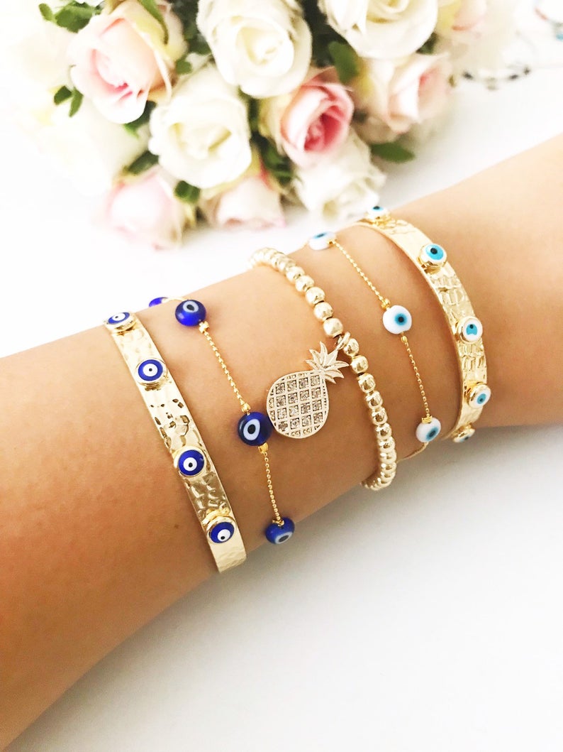 Gold Evil Eye Bracelet Set featuring adjustable bangles and tiny evil eye beads, showcasing handmade craftsmanship and durable stainless steel.