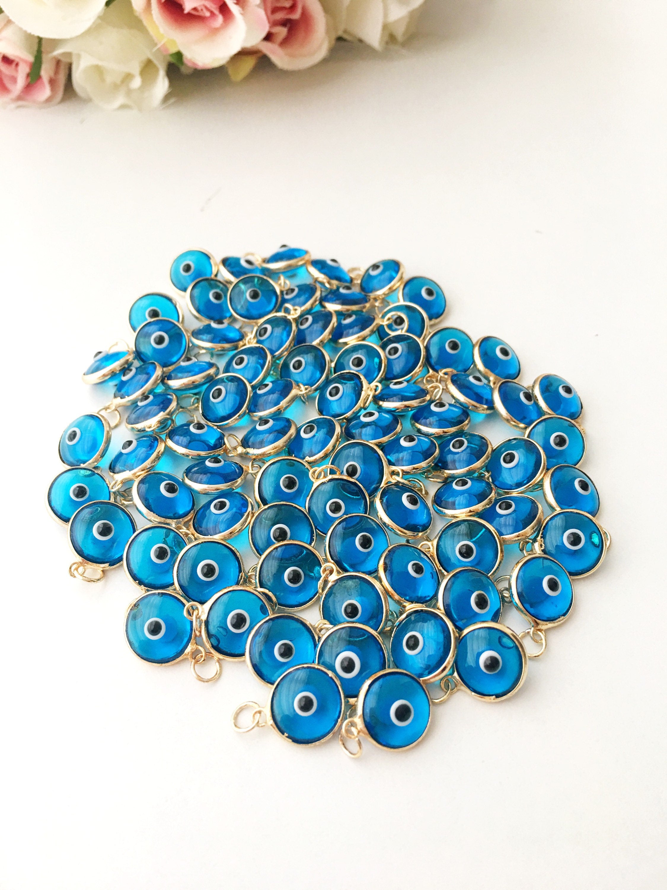 Gold evil eye charm featuring blue evil eye beads, perfect for DIY jewelry making, showcasing a delicate design and vibrant colors.