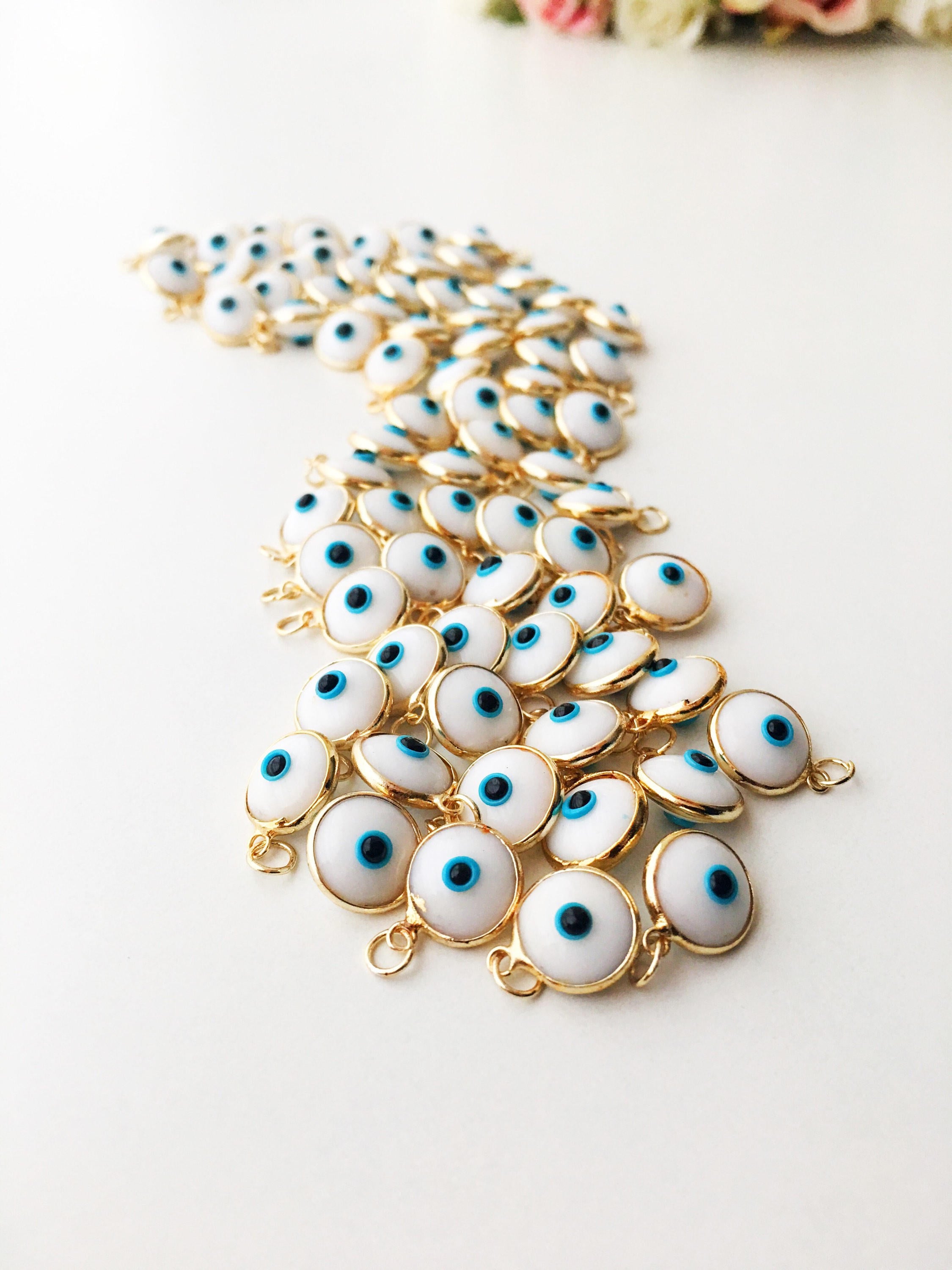 Gold evil eye charm featuring blue evil eye beads, perfect for DIY jewelry making, showcasing a delicate design and vibrant colors.