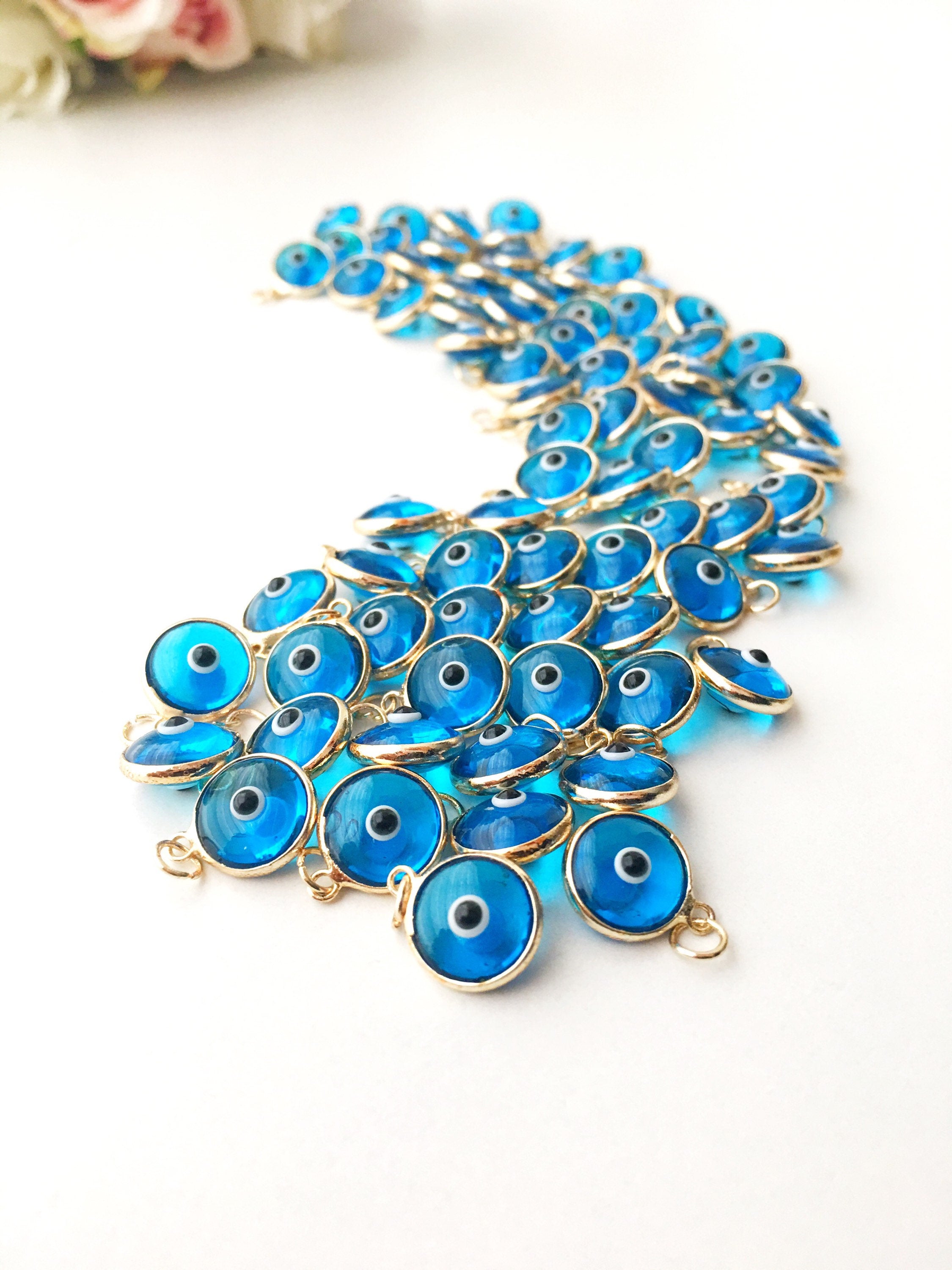 Gold evil eye charm featuring blue evil eye beads, perfect for DIY jewelry making, showcasing a delicate design and vibrant colors.