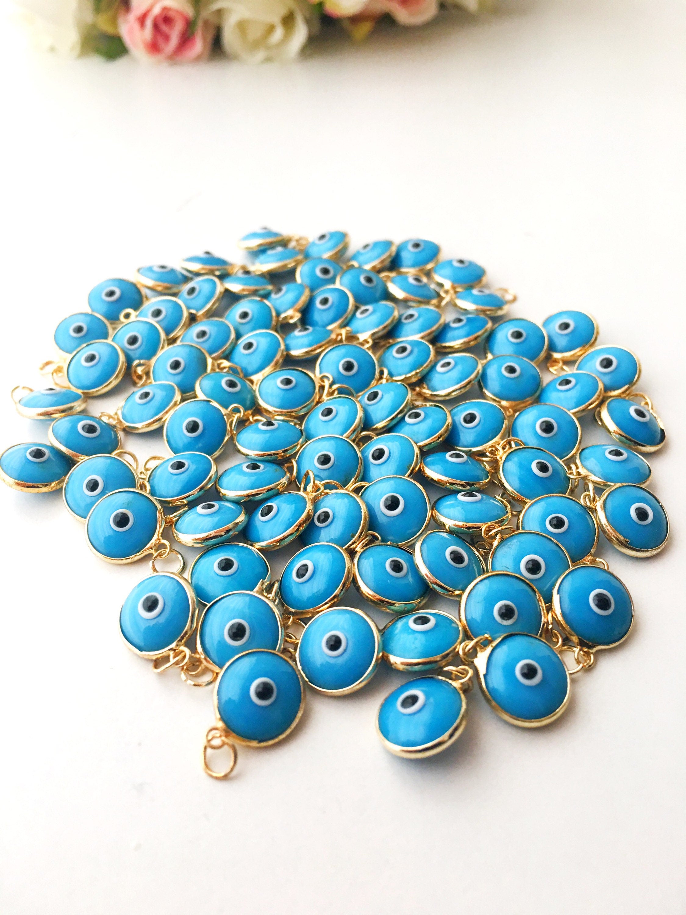 Gold evil eye charm featuring blue evil eye beads, perfect for DIY jewelry making, showcasing a delicate design and vibrant colors.