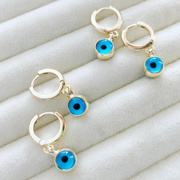 A pair of elegant gold hoop earrings featuring blue evil eye beads, showcasing a handmade design with double-sided glass beads.