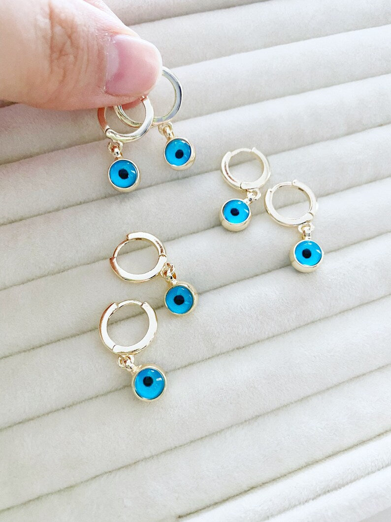 A pair of elegant gold hoop earrings featuring blue evil eye beads, showcasing a handmade design with double-sided glass beads.