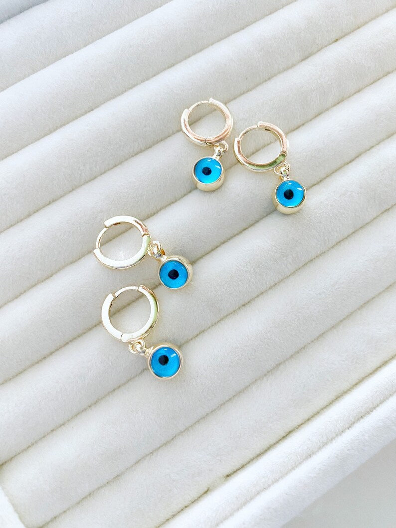 A pair of elegant gold hoop earrings featuring blue evil eye beads, showcasing a handmade design with double-sided glass beads.