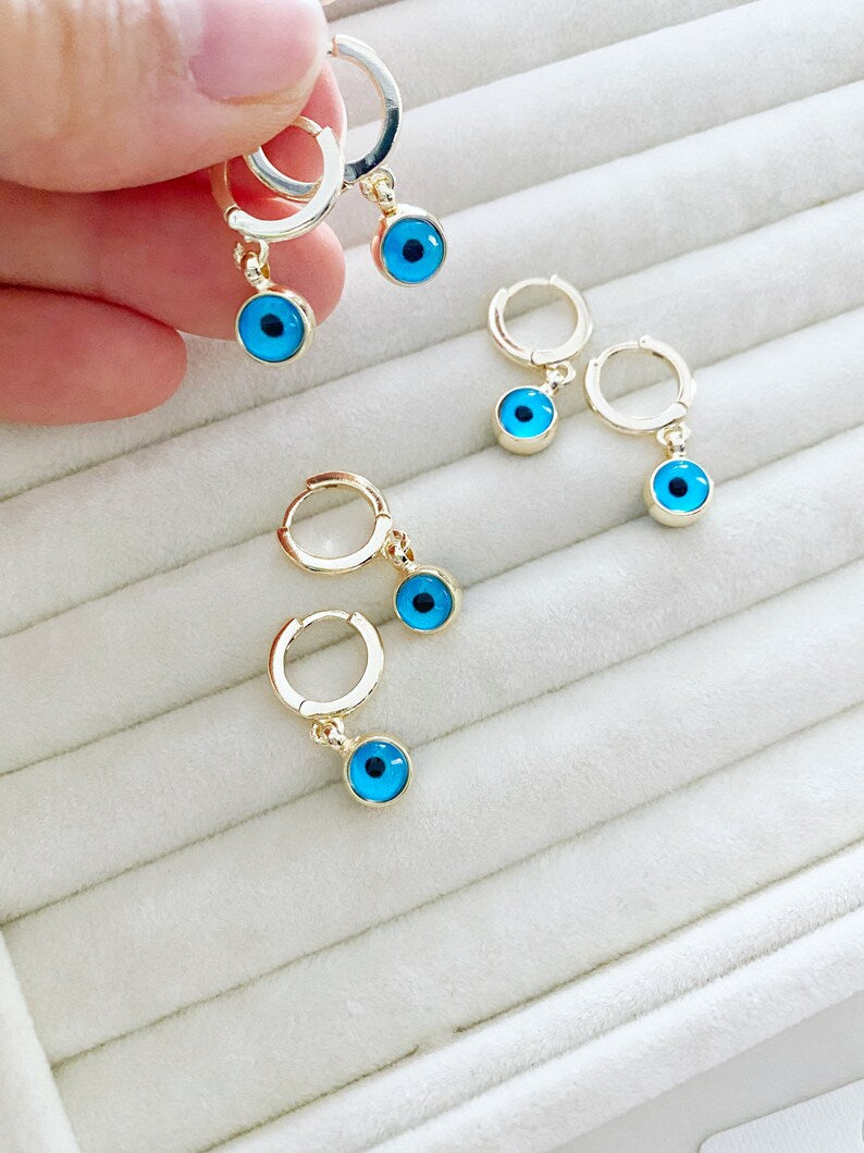 A pair of elegant gold hoop earrings featuring blue evil eye beads, showcasing a handmade design with double-sided glass beads.