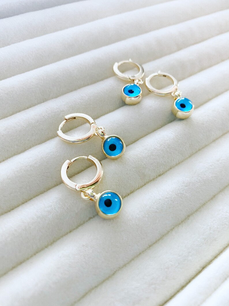 A pair of elegant gold hoop earrings featuring blue evil eye beads, showcasing a handmade design with double-sided glass beads.