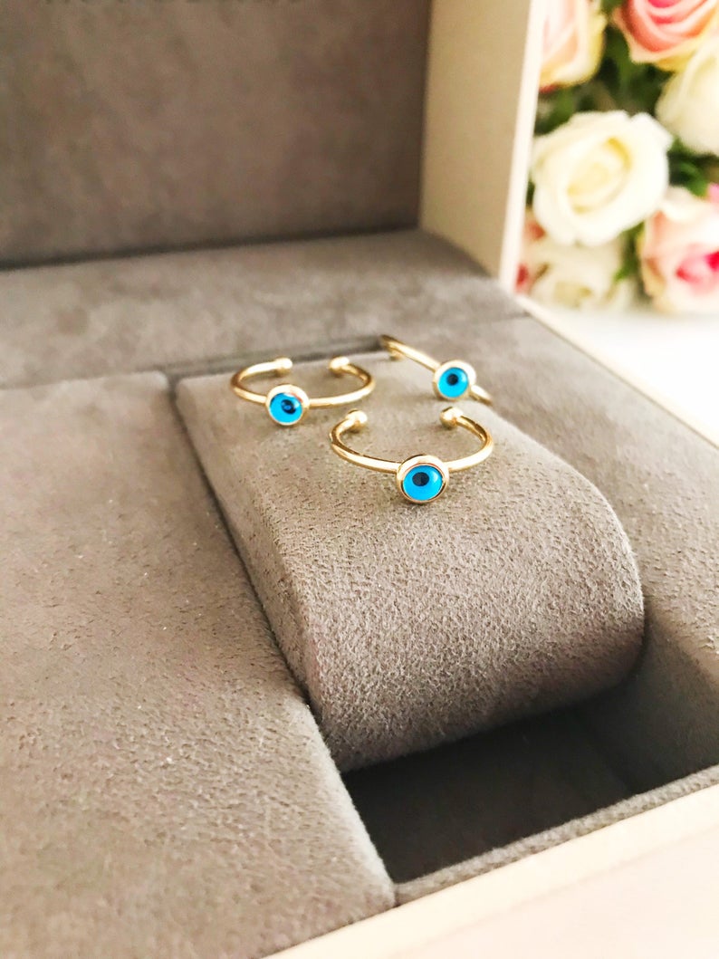 A delicate gold evil eye ring featuring a round blue evil eye bead on a thin adjustable band, perfect for everyday wear.