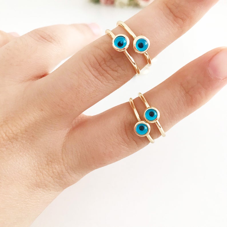 A delicate gold evil eye ring featuring a round blue evil eye bead on a thin adjustable band, perfect for everyday wear.