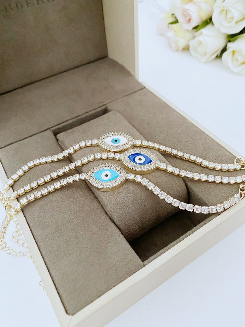 Gold Evil Eye Tennis Bracelet featuring a blue evil eye design, adjustable stainless steel material, and elegant gold finish.