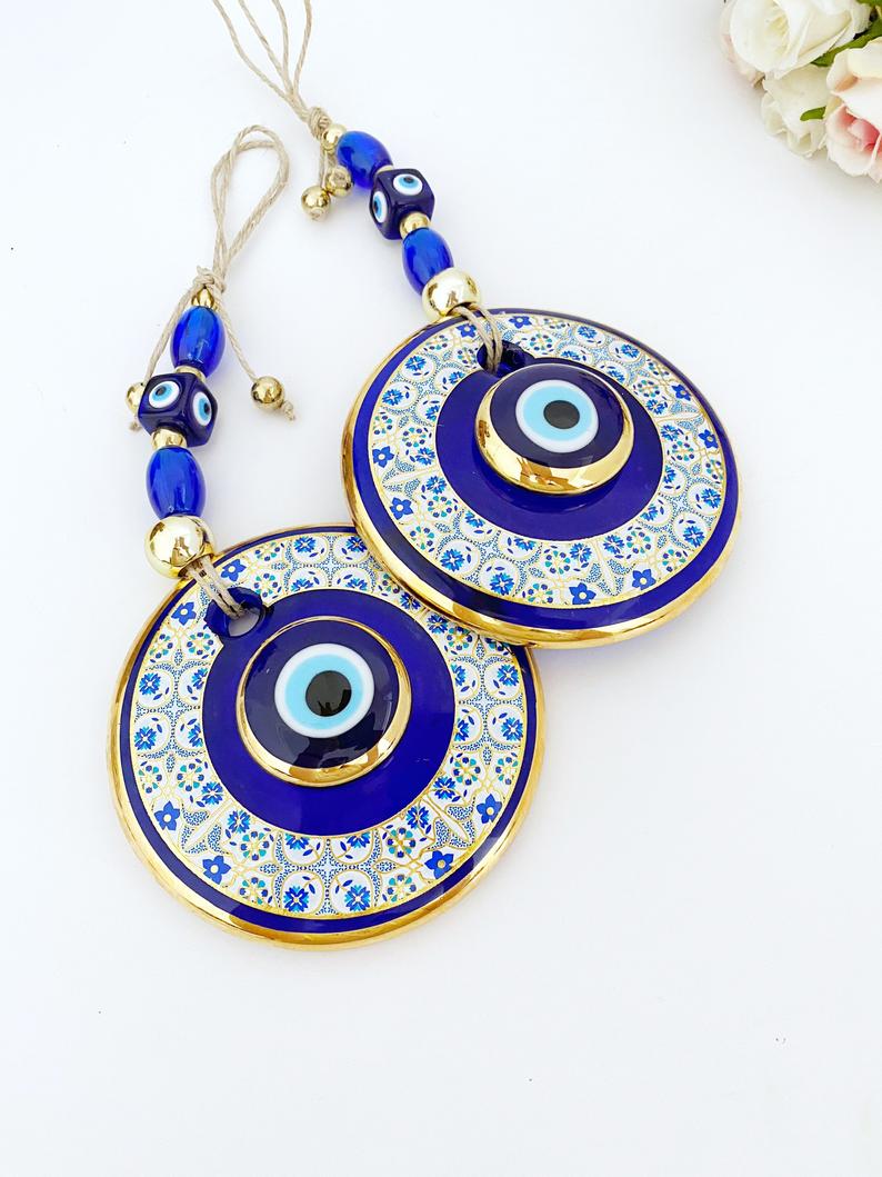 Gold Evil Eye Wall Hanging featuring a white patterned design, handmade with intricate details, symbolizing protection and good fortune.