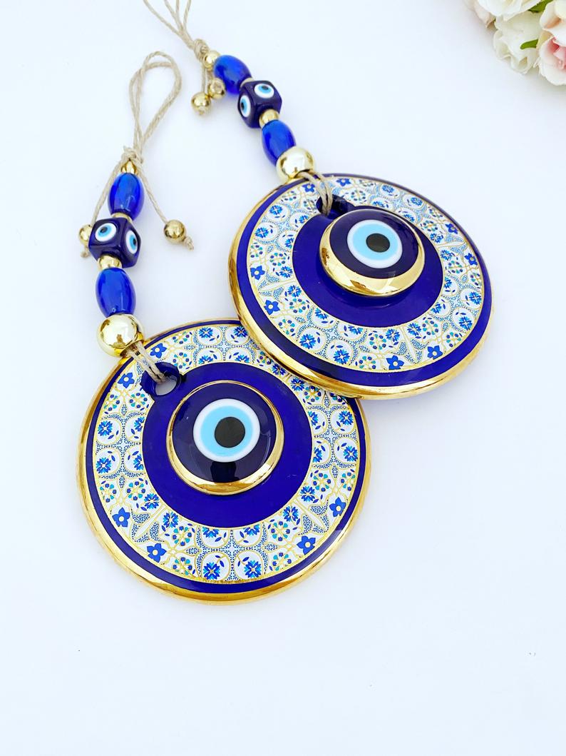 Gold Evil Eye Wall Hanging featuring a white patterned design, handmade with intricate details, symbolizing protection and good fortune.