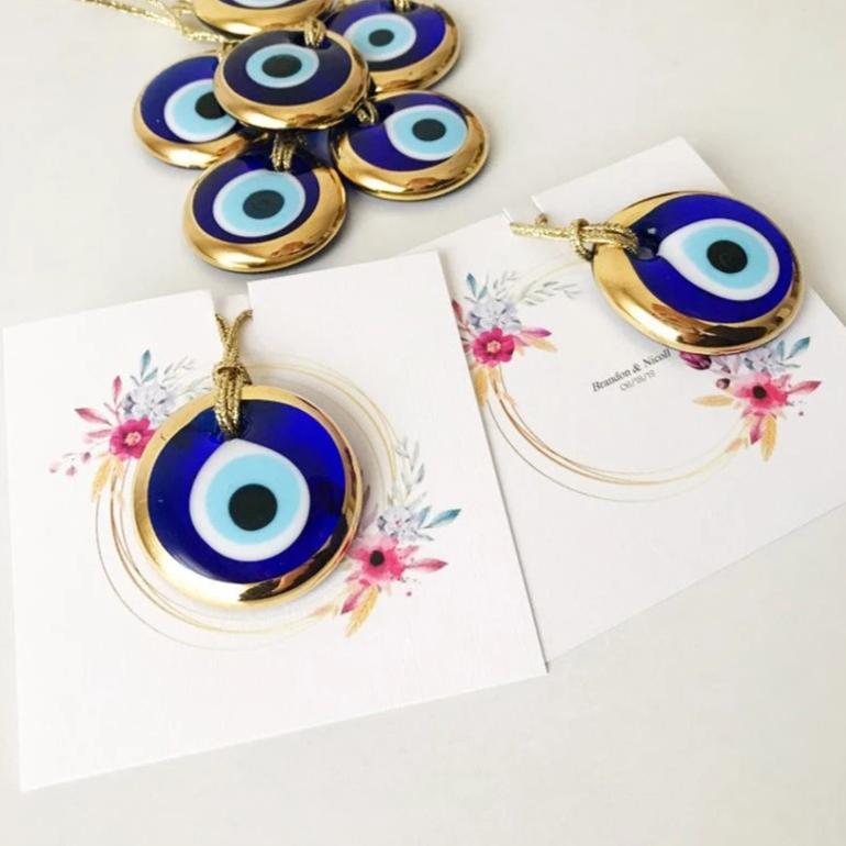 Gold evil eye bead wedding giveaway with personalized card, showcasing intricate design and vibrant colors.