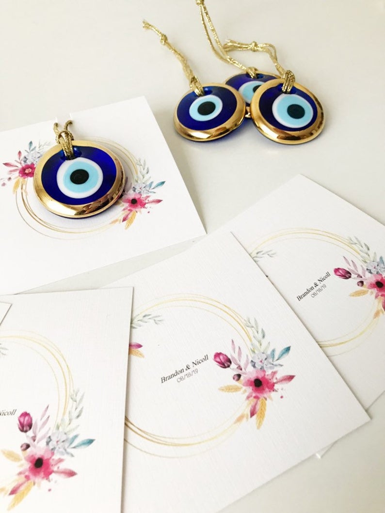 Gold evil eye bead wedding giveaway with personalized card, showcasing intricate design and vibrant colors.