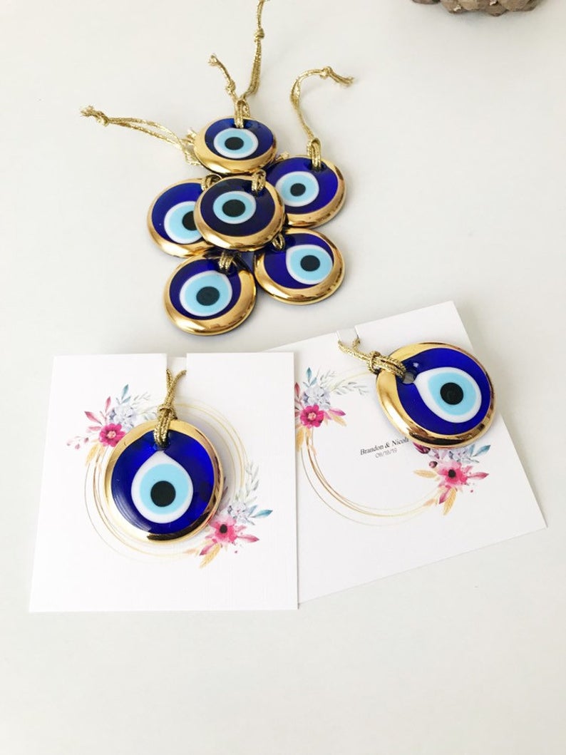 Gold evil eye bead wedding giveaway with personalized card, showcasing intricate design and vibrant colors.