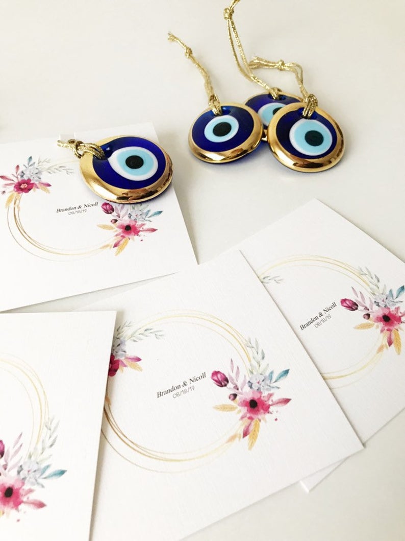 Gold evil eye bead wedding giveaway with personalized card, showcasing intricate design and vibrant colors.