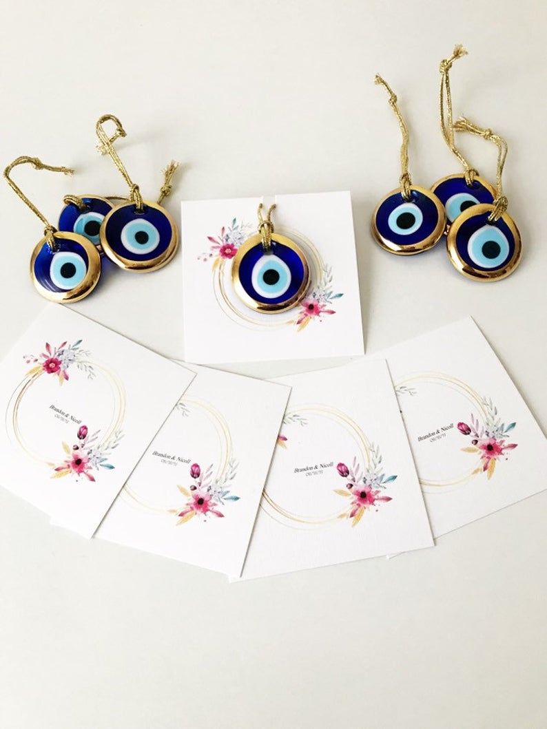 Gold evil eye bead wedding giveaway with personalized card, showcasing intricate design and vibrant colors.