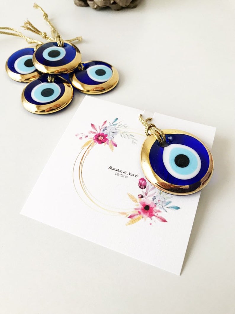 Gold evil eye bead wedding giveaway with personalized card, showcasing intricate design and vibrant colors.