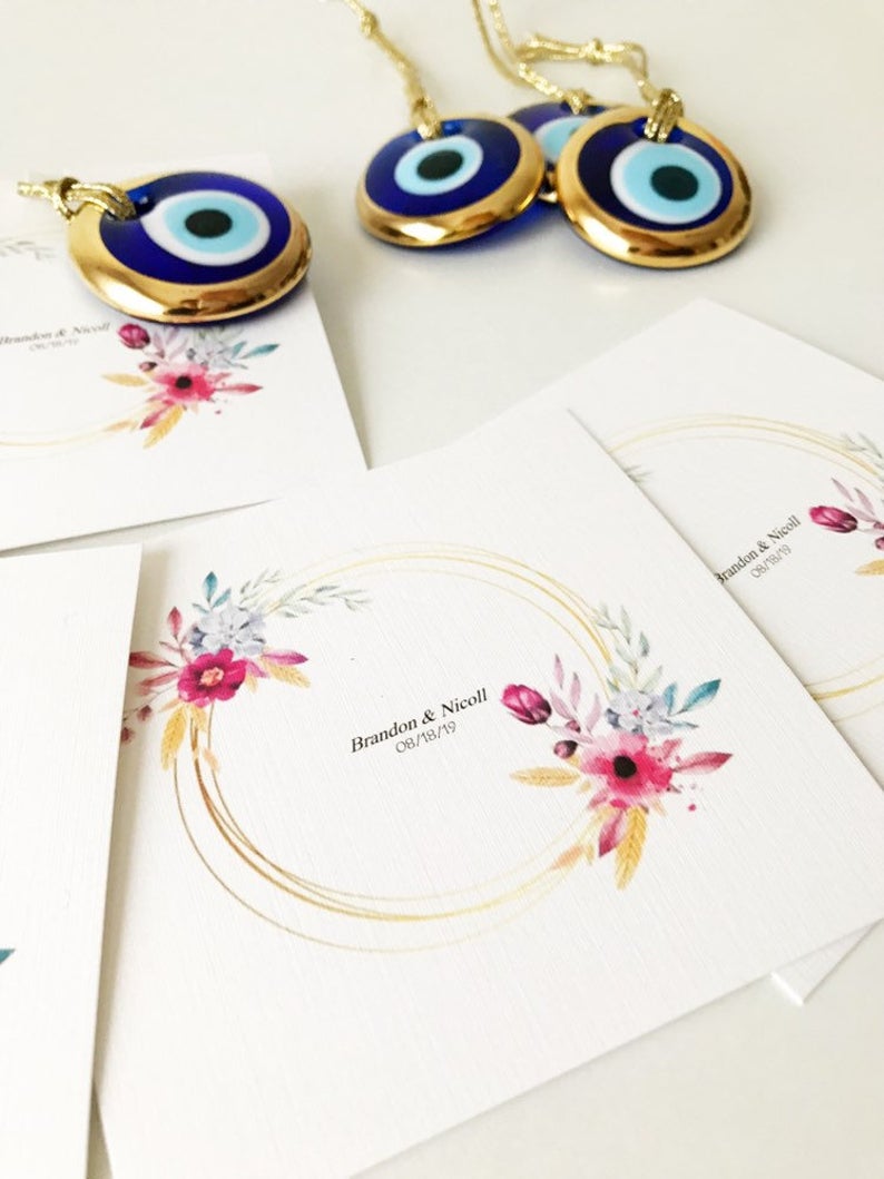 Gold evil eye bead wedding giveaway with personalized card, showcasing intricate design and vibrant colors.