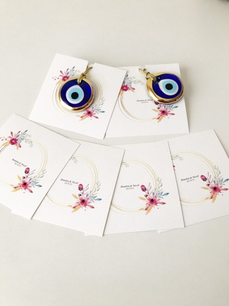 Gold evil eye bead wedding giveaway with personalized card, showcasing intricate design and vibrant colors.