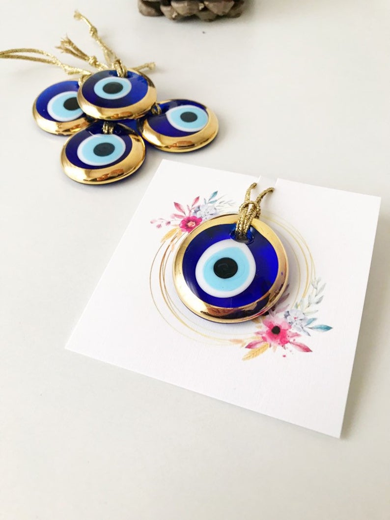 Gold evil eye bead wedding giveaway with personalized card, showcasing intricate design and vibrant colors.