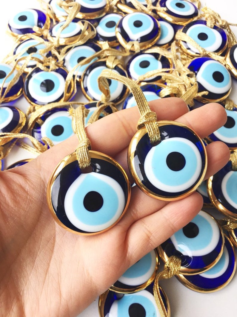 Gold evil eye bead wedding giveaway with personalized card, showcasing intricate design and vibrant colors.