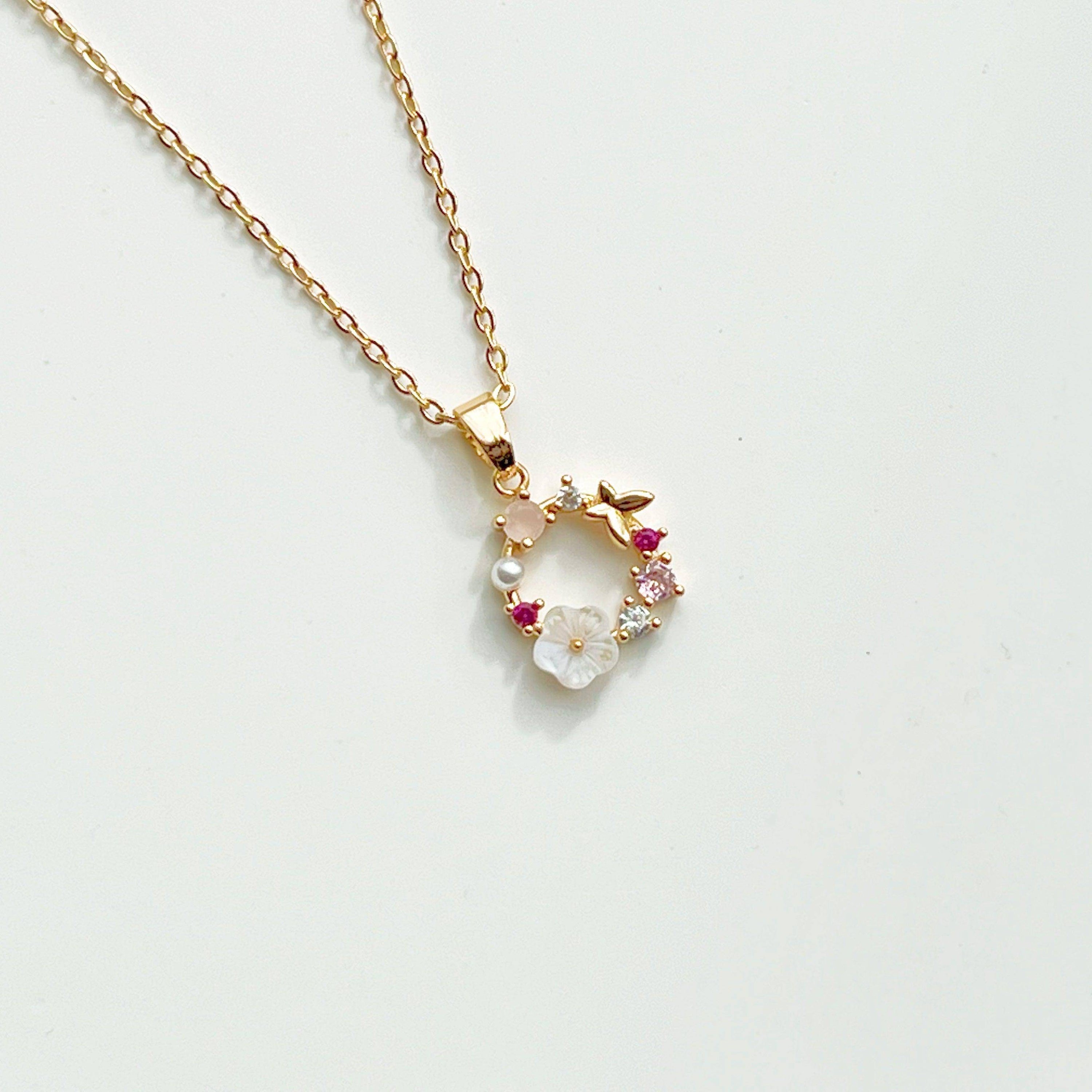 Gold Flower Wreath Charm Necklace featuring pink crystals and pearls, elegantly designed for meaningful gifting.