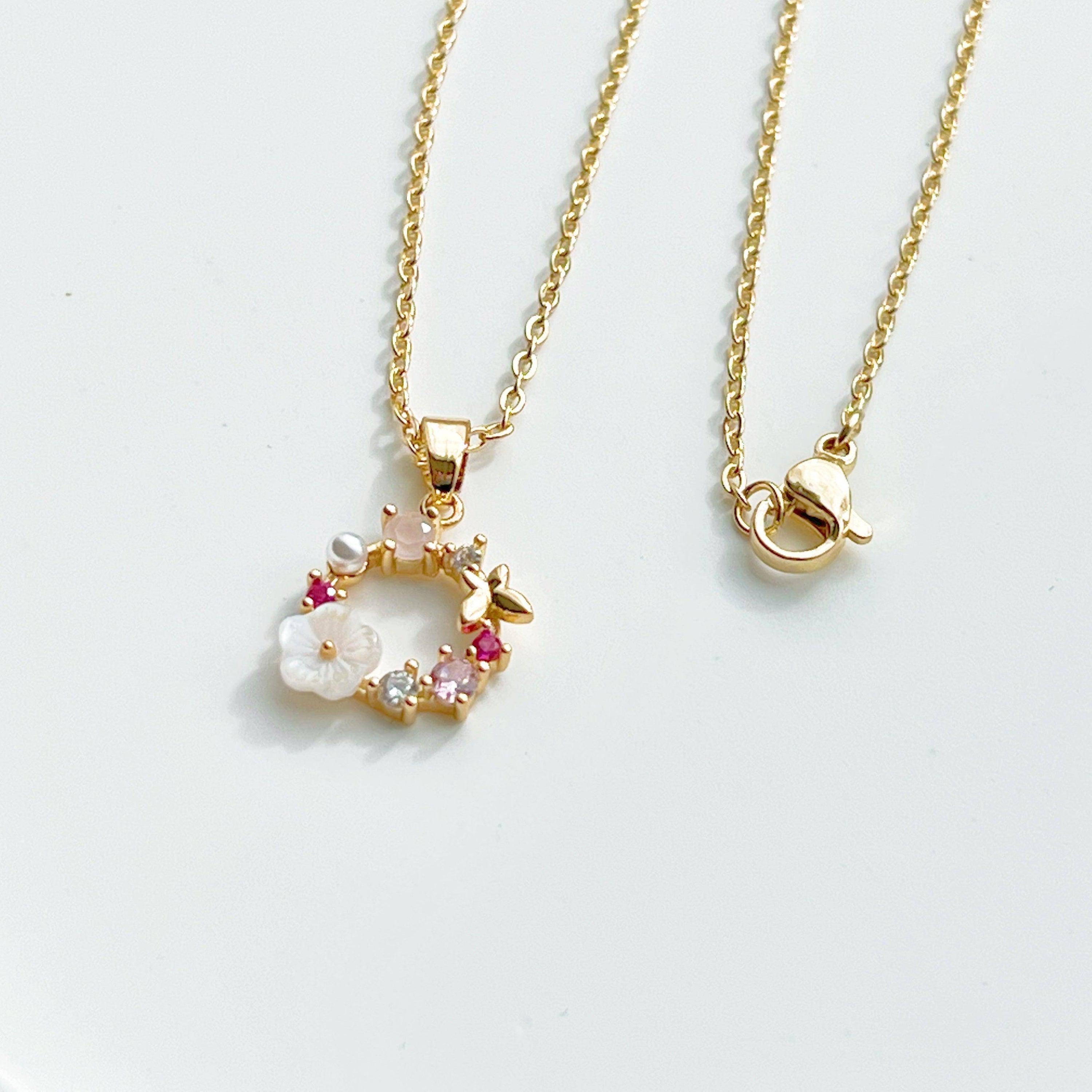 Gold Flower Wreath Charm Necklace featuring pink crystals and pearls, elegantly designed for meaningful gifting.