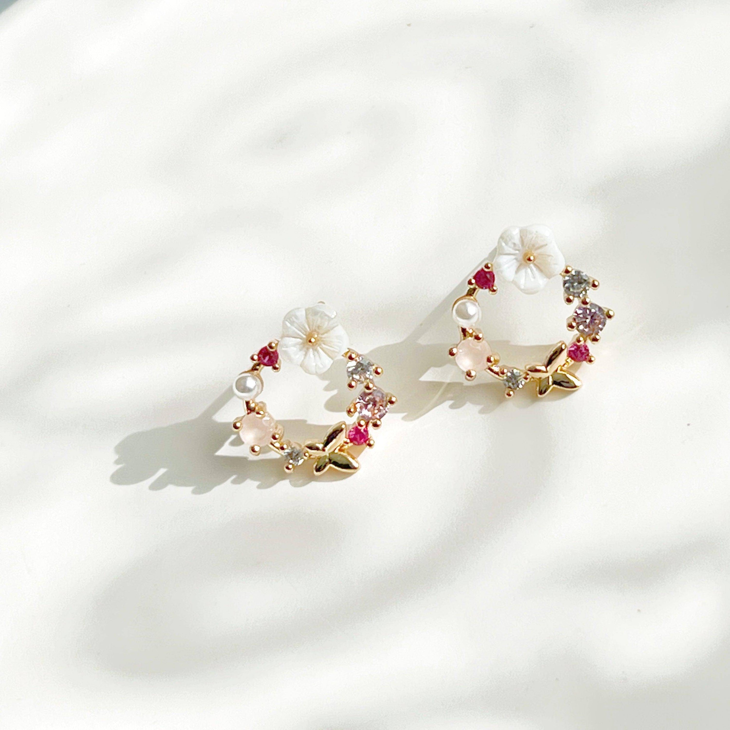 Elegant gold flower wreath earrings with pink crystals and pearls, showcasing a delicate floral design.