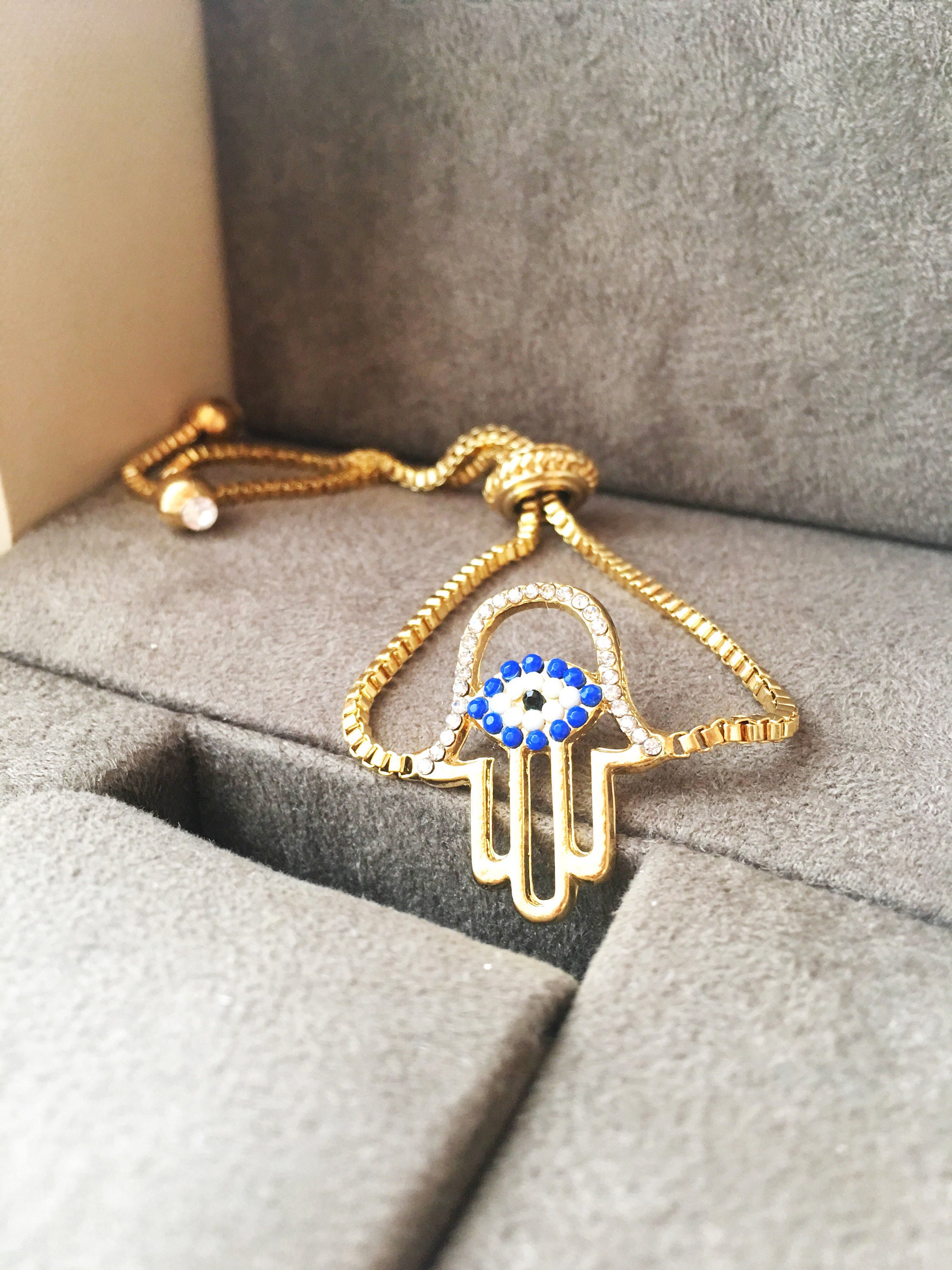 Gold Hamsa Evil Eye Bracelet featuring blue evil eye beads and adjustable stainless steel design.