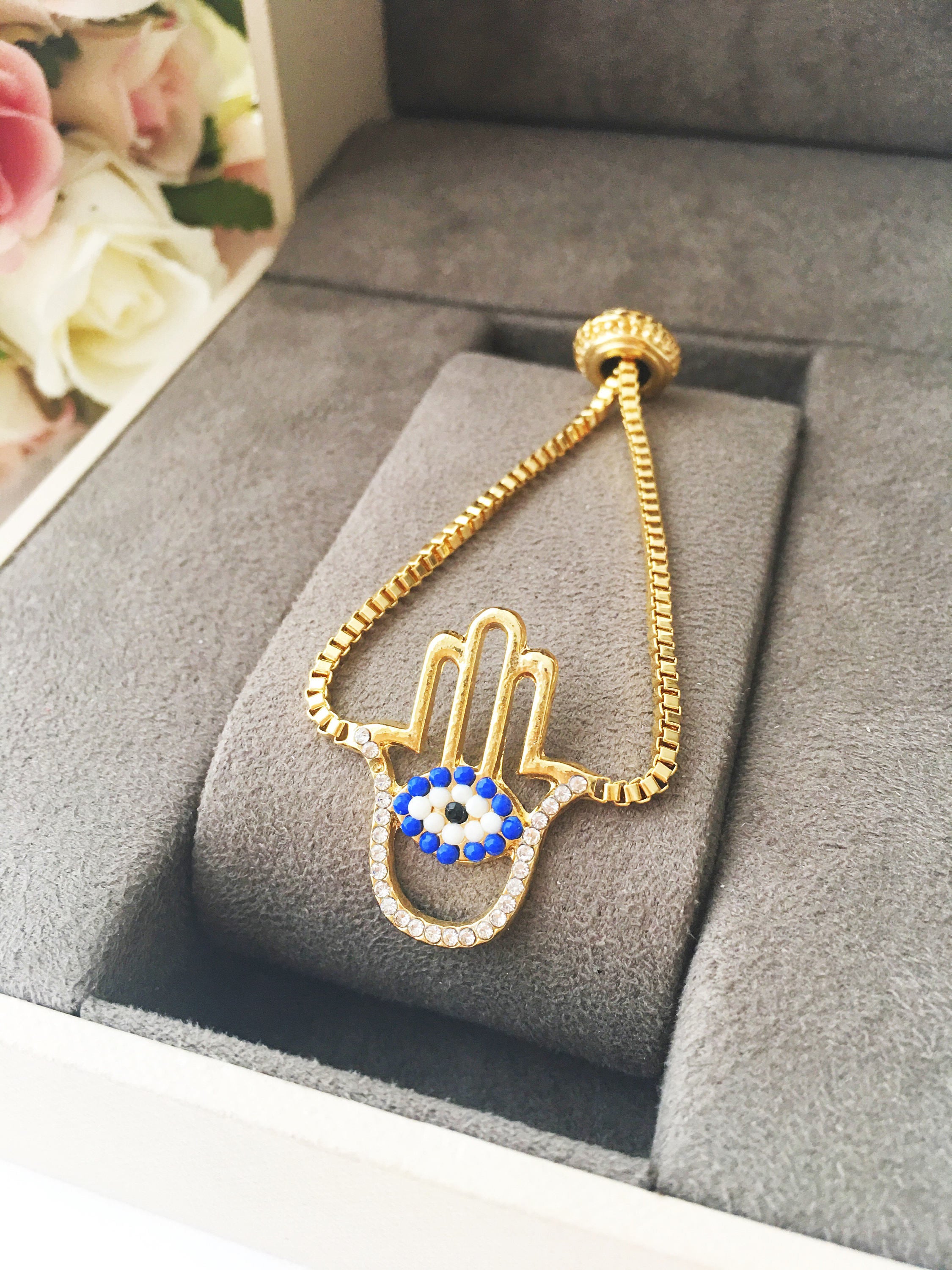 Gold Hamsa Evil Eye Bracelet featuring blue evil eye beads and adjustable stainless steel design.