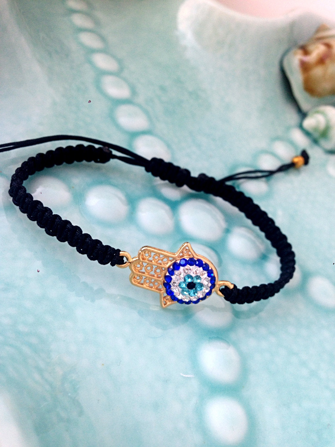 Gold Hamsa Evil Eye Bracelet featuring a silver-plated hamsa hand and evil eye charm on a black macrame band.