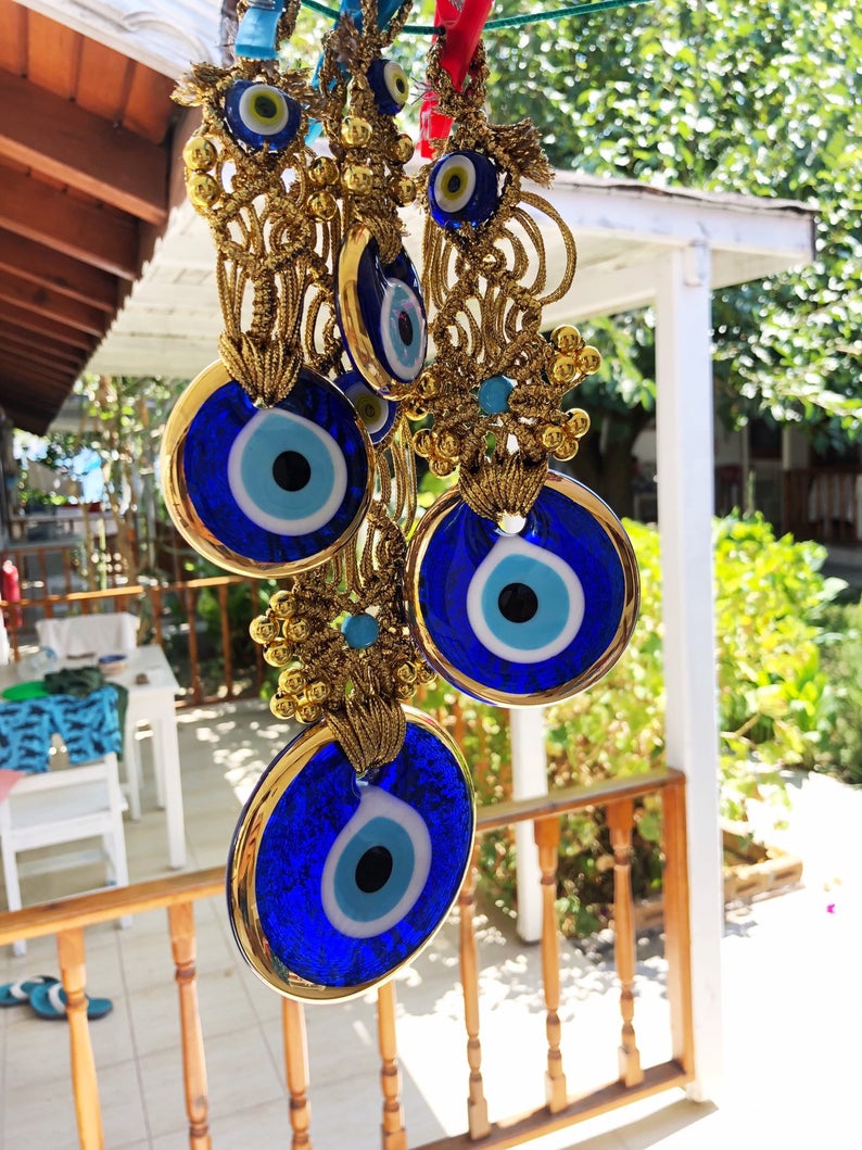 Gold macrame evil eye wall hanging featuring intricate designs and vibrant evil eye beads, symbolizing protection and good luck.