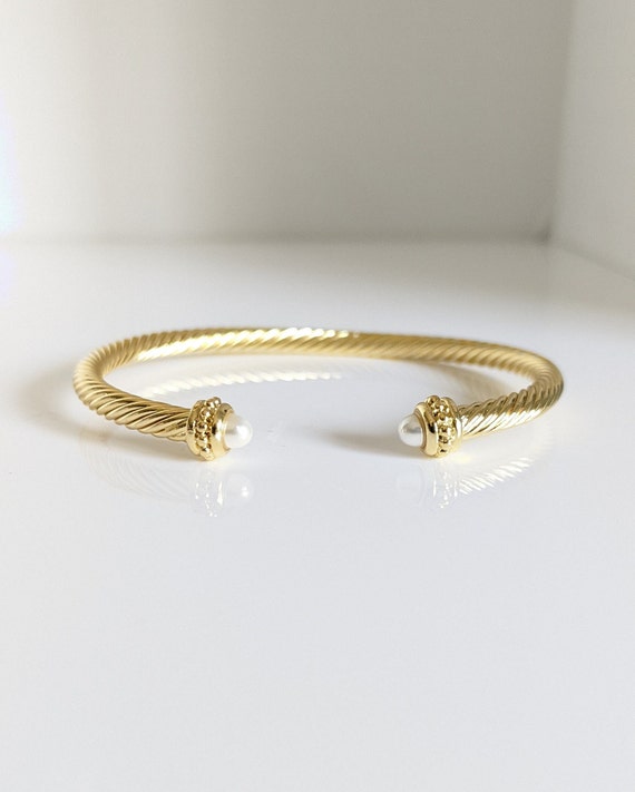 Elegant Gold Pearl Bangle Bracelet with twisted cable design and synthetic pearl accent, showcasing its adjustable fit and stylish appearance.