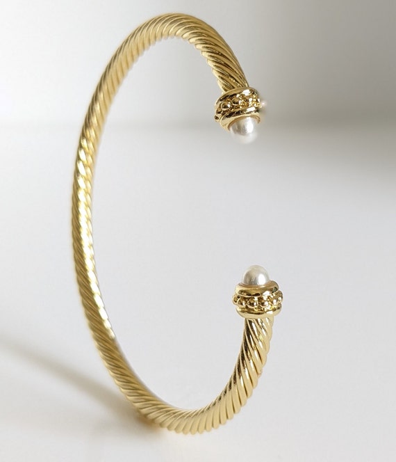 Elegant Gold Pearl Bangle Bracelet with twisted cable design and synthetic pearl accent, showcasing its adjustable fit and stylish appearance.