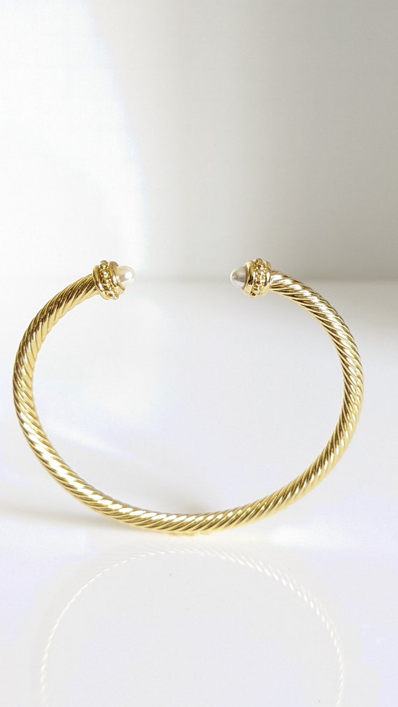 Elegant Gold Pearl Bangle Bracelet with twisted cable design and synthetic pearl accent, showcasing its adjustable fit and stylish appearance.